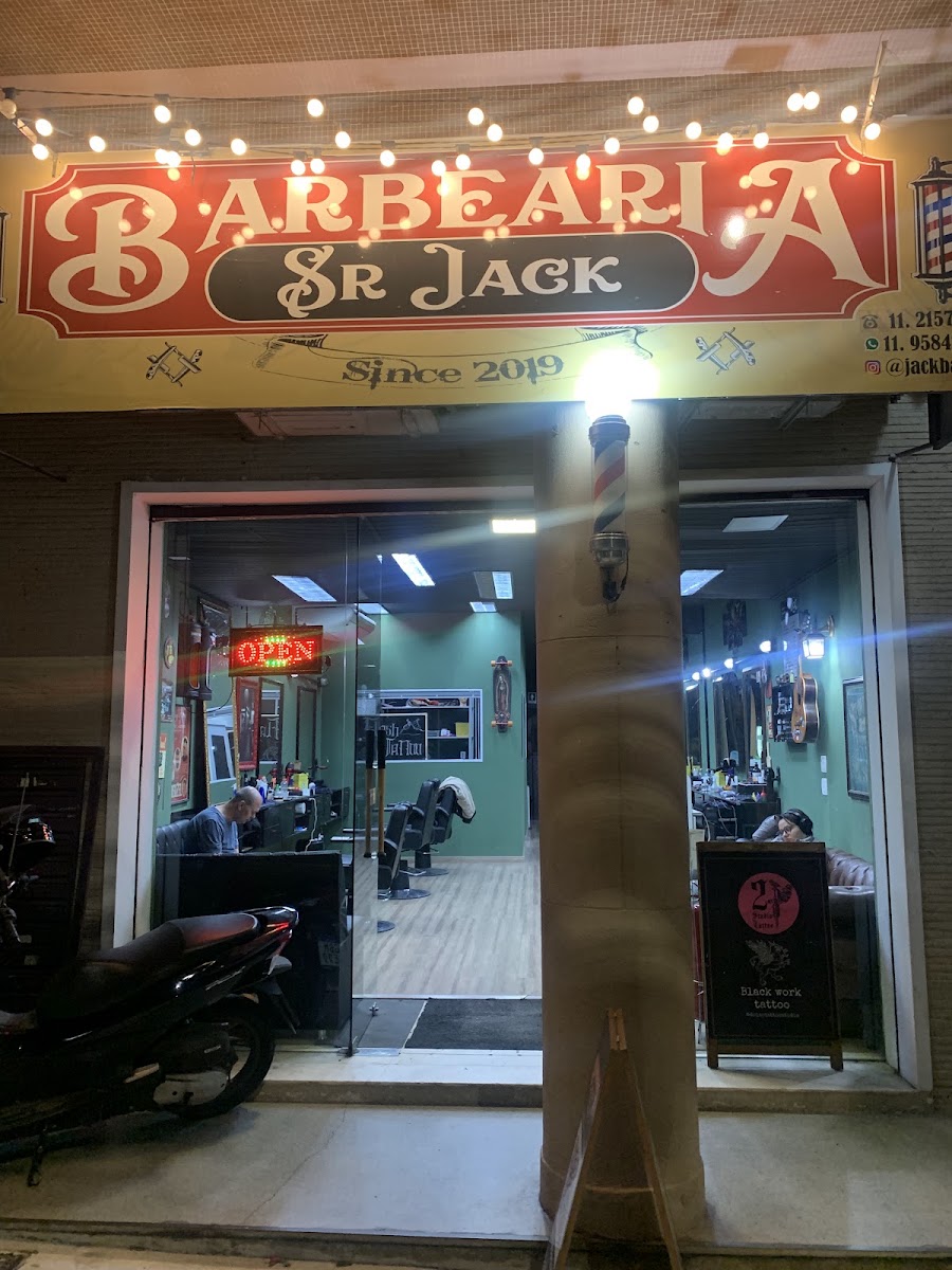 Letreiro iluminado da Barbearia Senhor Jack visto da rua à noite